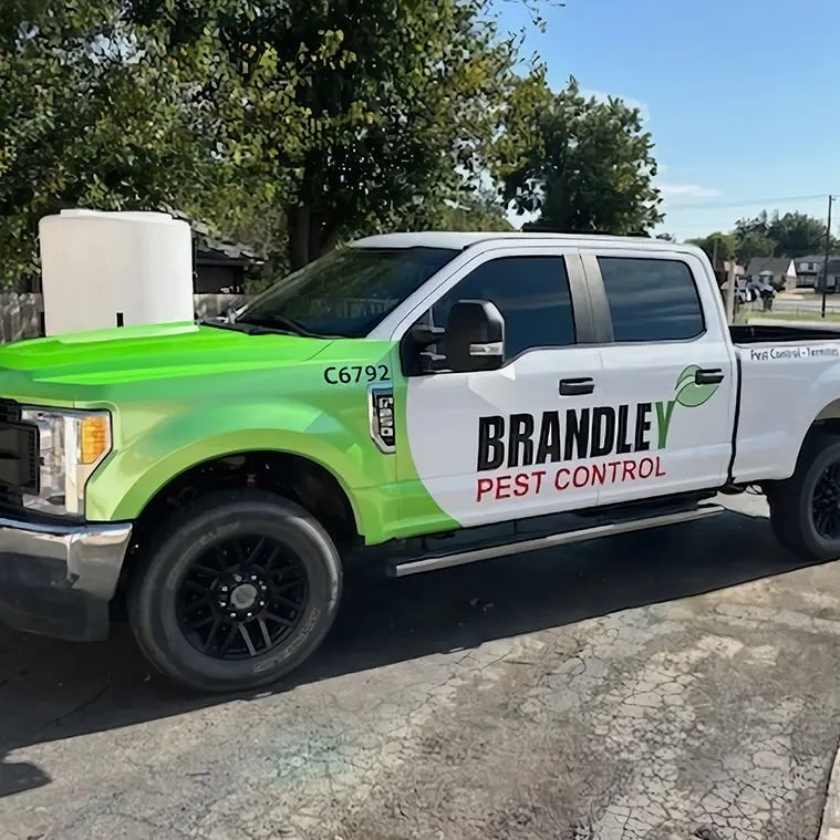 White and green Brandley Pest Control pickup truck with company name and leaf logo parked on a driveway