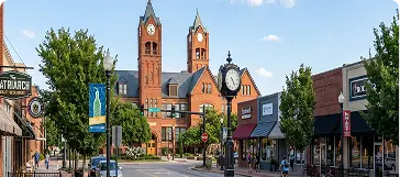 Main street with red-brick municipal building with twin clock towers, street clock and storefronts